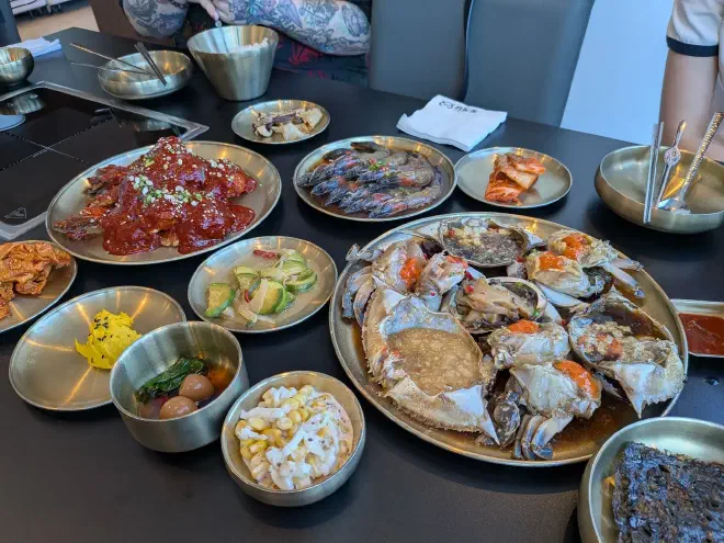 Multiple metal plates on a black table with various colourful foods on them