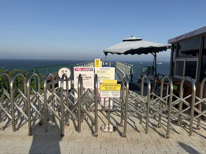 A metal barricade pulled across a path with multiple signs on it