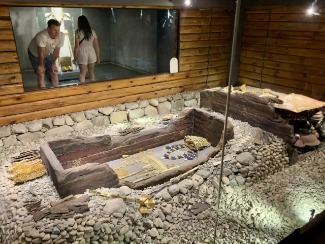 The main coffin of the tomb An old wooden coffin with gold regalia inside a glass room