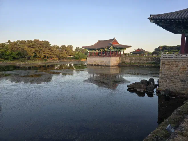 The pavillions overlooking the pond Two red wooden pavillions on stone bases overlook a stagnant pond with trees surrounding it