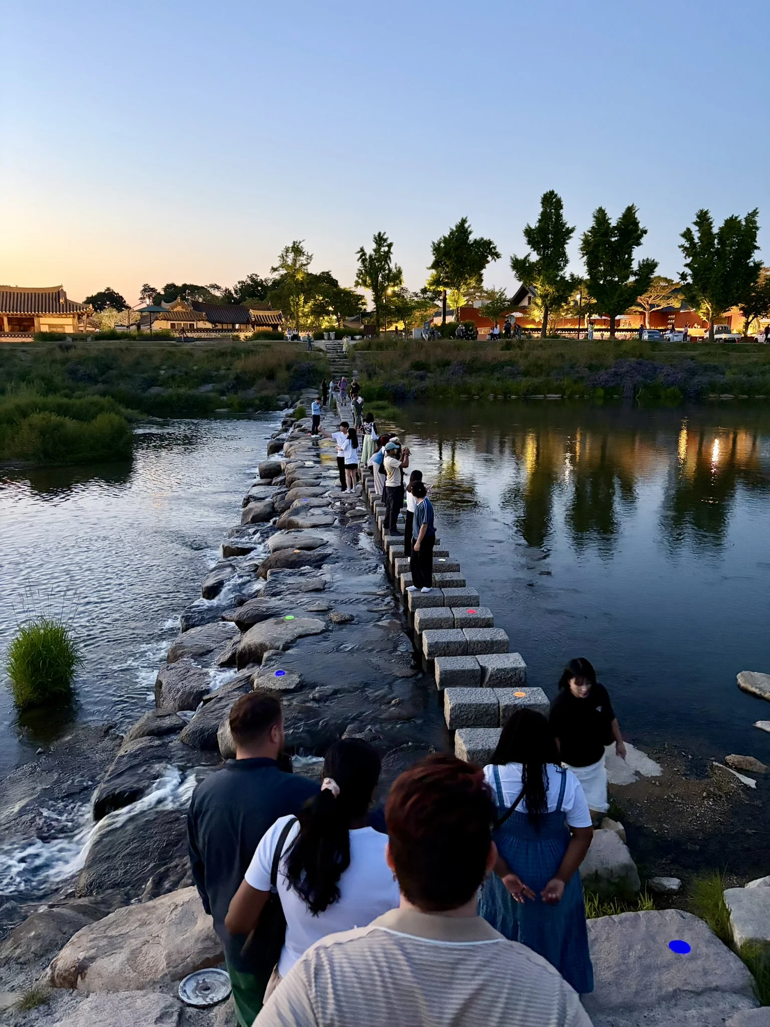 Balance for that Instagram shot People taking pictures stand on stepping stones over a river