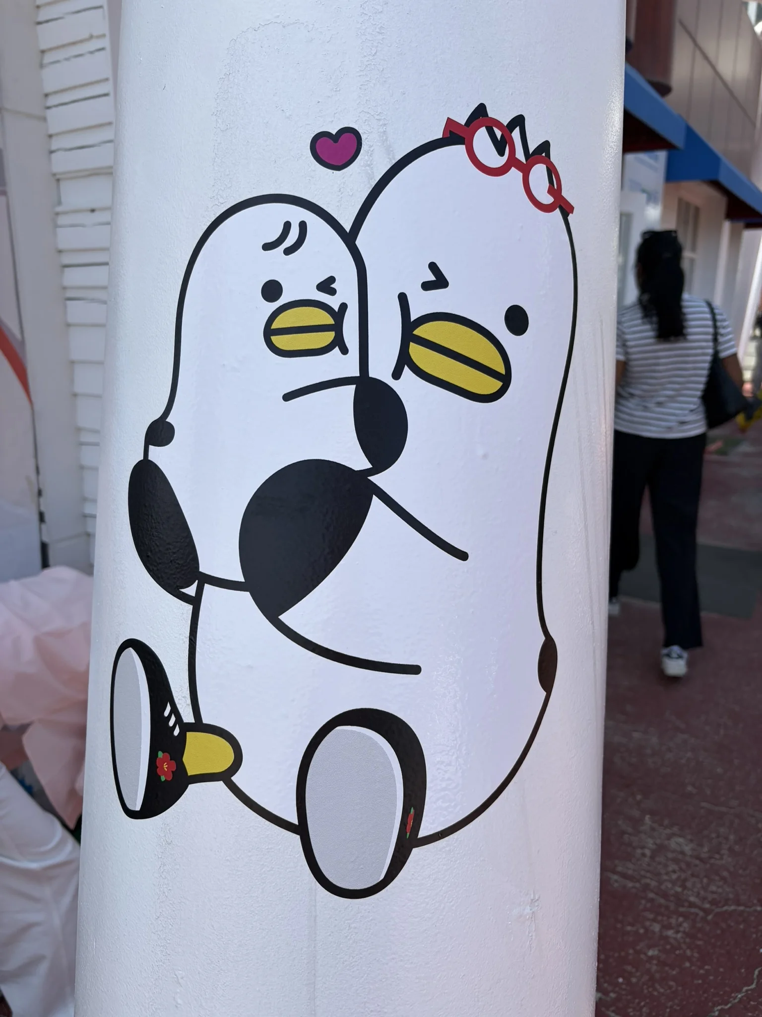 Boogi A lamppost with a sticker of a seagull with glasses holding a younger seagull