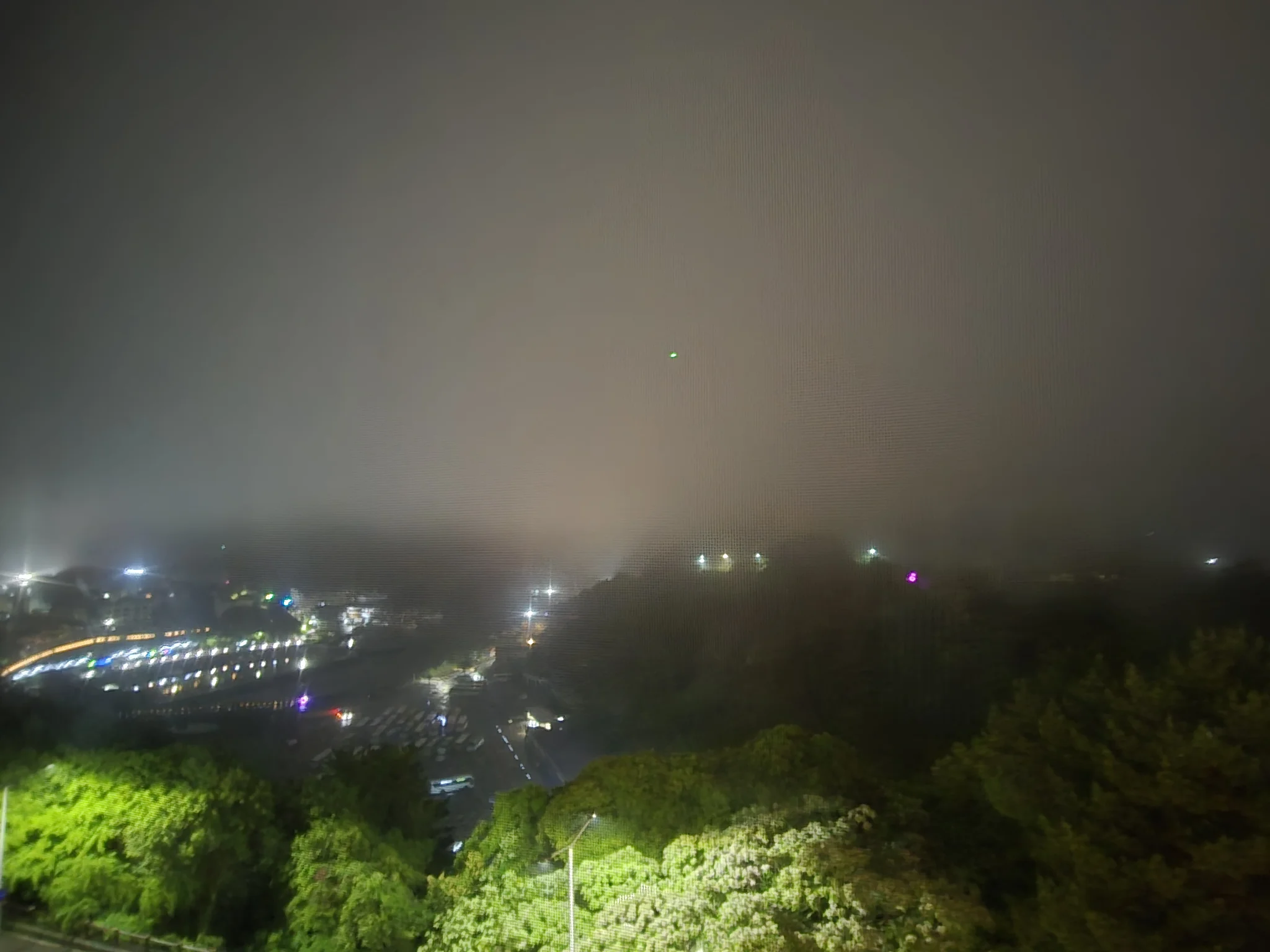 Weather outside our hotel overnight Nighttime view through thick fog revealing scattered city lights below