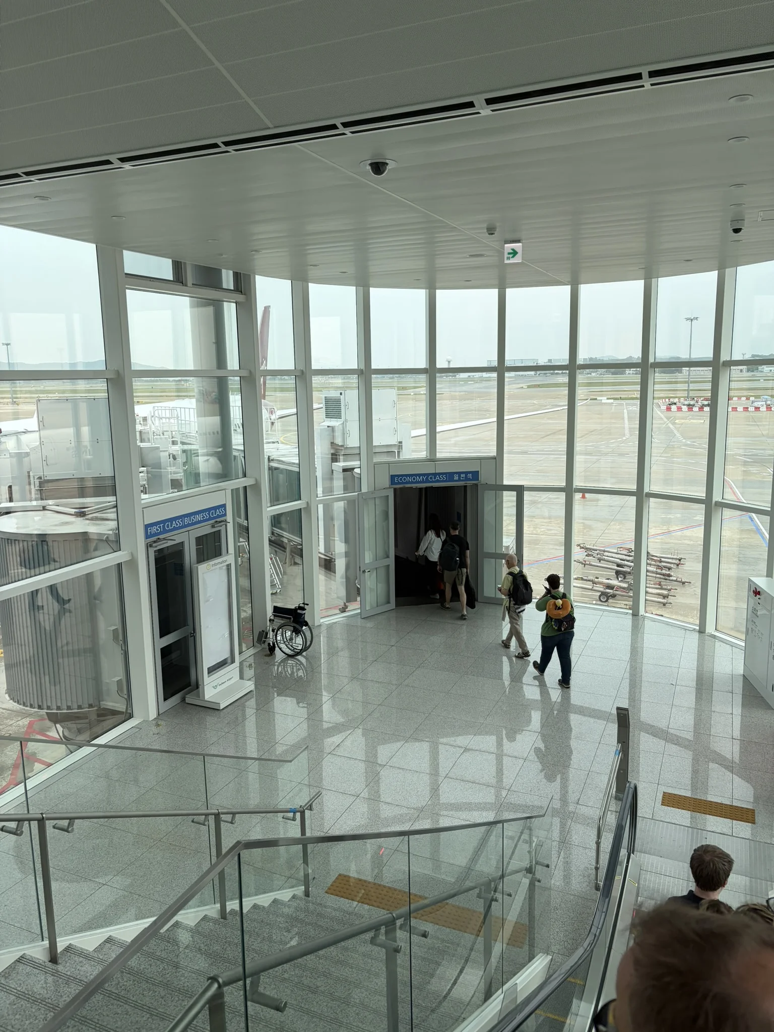 Our gateway back to the UK A tall windowed room with people exiting towards a plane