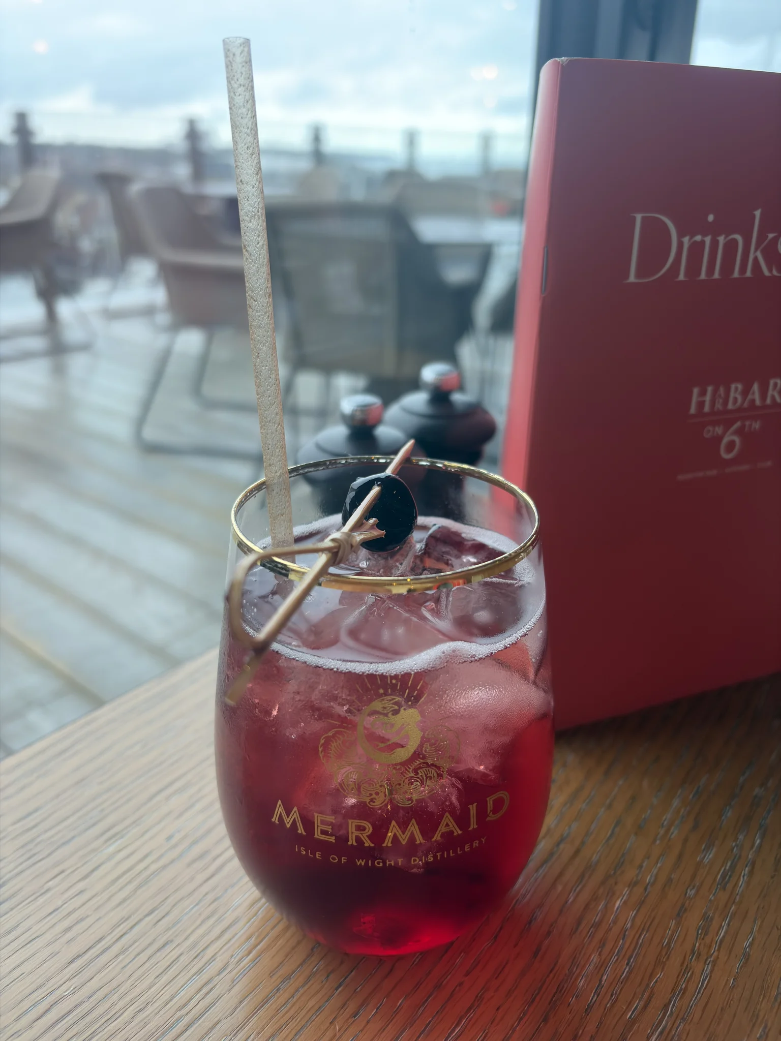 A red cocktail in a short glass on a wooden table