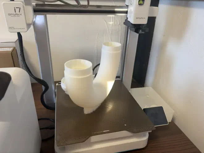 3D printed candy cane top A plastic 180 degree pipe sits on the printing plate of a 3D printer